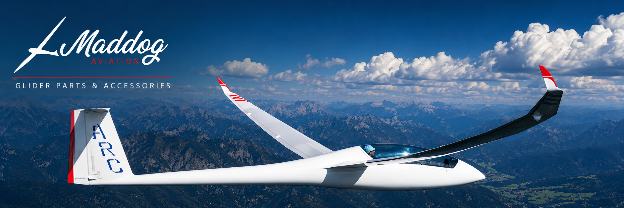 Glider soaring over mountainous landscape with Maddog Glider Parts & Accessories logo.